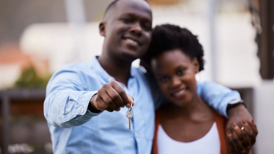 A couple posing with their new home in the background after receiving ILA for new home buyers